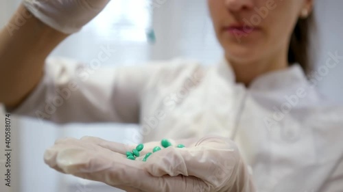 Young female doctor pouring medicine from a jar, pills in hand, concept of healthcare, pharmacy and treatment, close-up view.