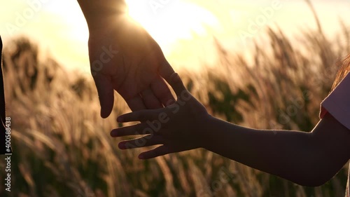 Close-up of mother and daughter hands joining together with sunset sunlight flare in natural background, Slow motion. Beautiful romantic moment between mother and litle child. Happy Family Concept