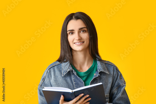 Young woman with book on color background