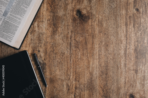 An open bible and notebook for bible study on a wooden desk.Top view flat lay.