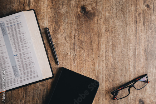 Vászonkép Open Bible and notebook on a wooden desk. Top view flat lay.