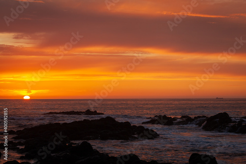 Flaming red sunset with cargo ship on the horizon