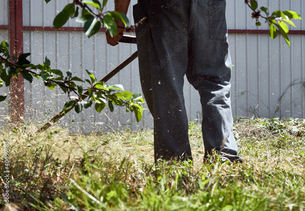 Worker mowing grass with lawnmower in backyard. Process of lawn trimming with hand mower Worker mowing grass with lawnmower in backyard. Process of lawn trimming with hand mower