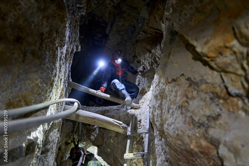 person with head torch climbing through the darkness of a silver mine inside cero rico in Potosi in the high andes mountains of the Altiplano in Bolivia, South America