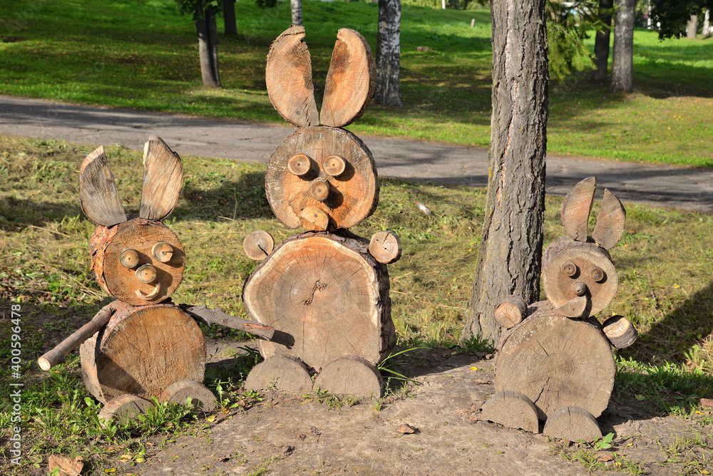 Three wooden hares on grassy lawn in park