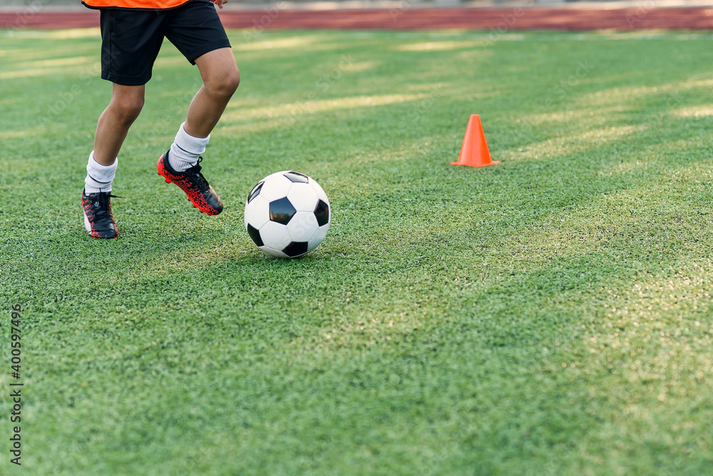 Soccer player kicking ball on field. Soccer players on training session. Close up footballer feet kicking ball on grass. Soccer player kicking ball on field. Soccer players on training session. Close up footballer feet kicking ball on grass.