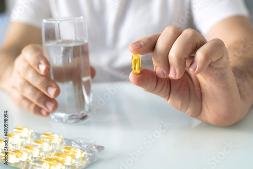 Man holding omega-3 fish oil nutritional supplement and glass of water
