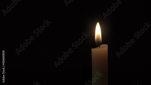 Candle. Close-up of a single candle flame burning against a black background.
