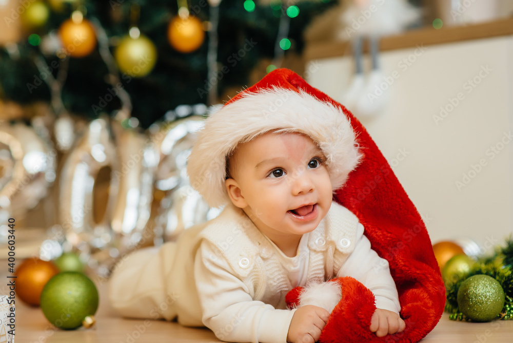 Cute smiling baby is lying under a festive Christmas tree and playing with gifts. Christmas and New Year celebrations Cute smiling baby is lying under a festive Christmas tree and playing with gifts. Christmas and New Year celebrations