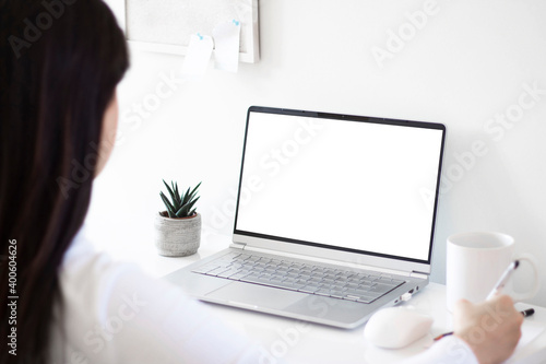 woman hand using laptop with mock up white screen and writing notes. work from home concept. 