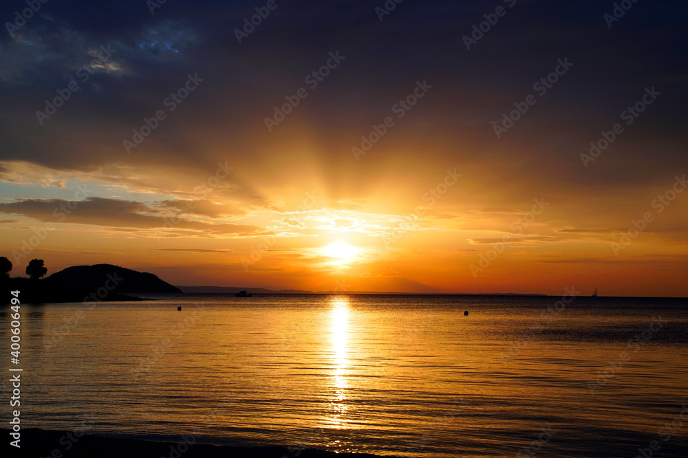 Fototapeta premium Evening in September. Sunset. Silhouettes on the horizon. Beautiful view . Greece Sithonia Aegean Sea. Skyline. Heavenly clouds in the rays of the setting sun.