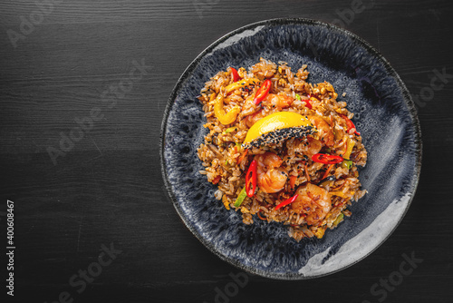 Fried rice with shrimp and vegetables in plate on wooden table background