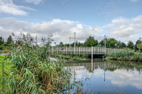 Rotterdam, The Netherlands, October 12, 2020: pedestrian bridge crossing a canal towards Park Zestienhoven neighbourhood, reflecting in the mirror-like water photo