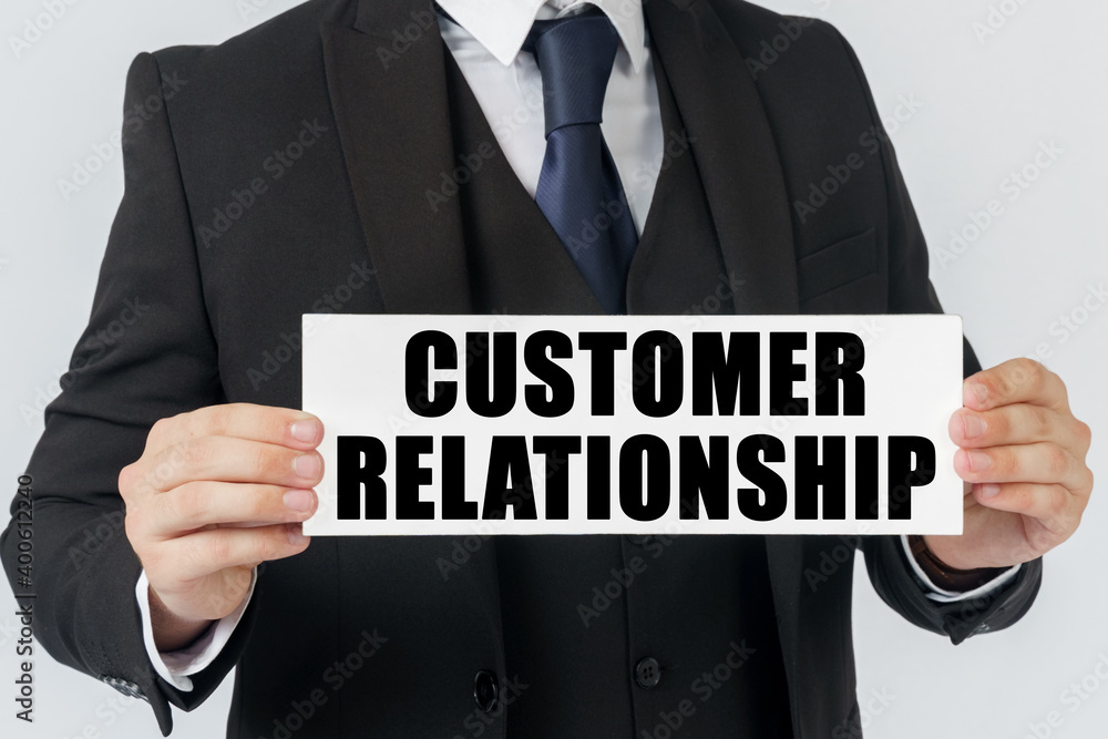 Obraz premium A businessman holds a sign in his hands which says - CUSTOMER RELATIONSHIP
