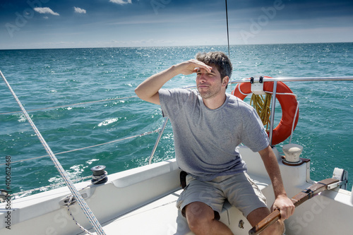 Young man on sailboat looking for direction while sailing