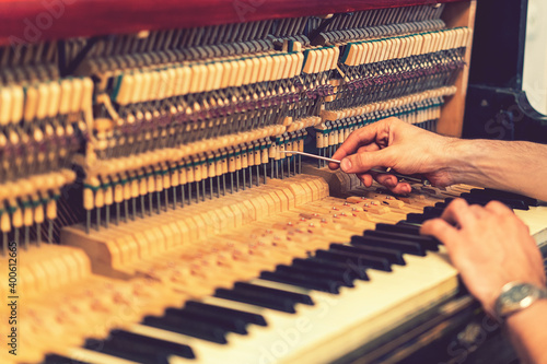 Piano tuning process. closeup of hand and tools of tuner working on grand piano. Detailed view of Upright Piano during a tuning. toned