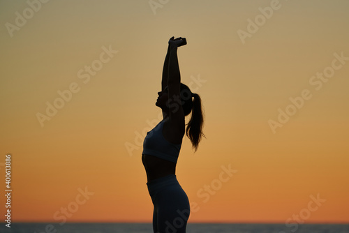 young spanish girl doing exercise in front of the mediterranean sea at sunset photo