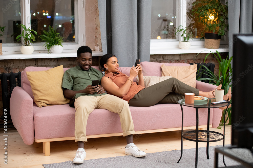 Obraz premium Teenage boy of African ethnicity and his mixed-race girlfriend using smartphones