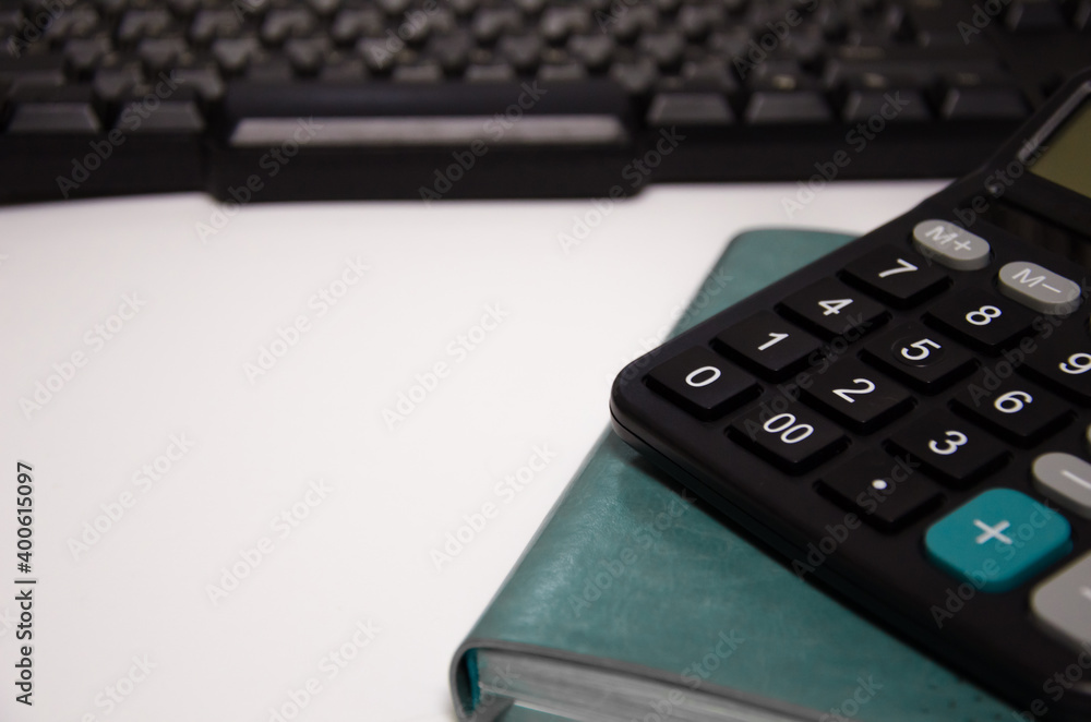 green notepad, calculator, keyboard lie on a white background green notepad, calculator, keyboard lie on a white background