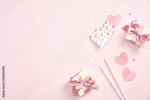 Valentines Day party concept. Gift boxes, greeting card, drinking straws, paper hearts, confetti on pink table. Flat lay, top view.