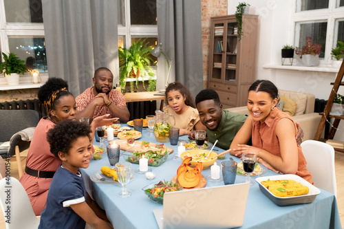 Big African family congratulating their friends in video chat by festive table