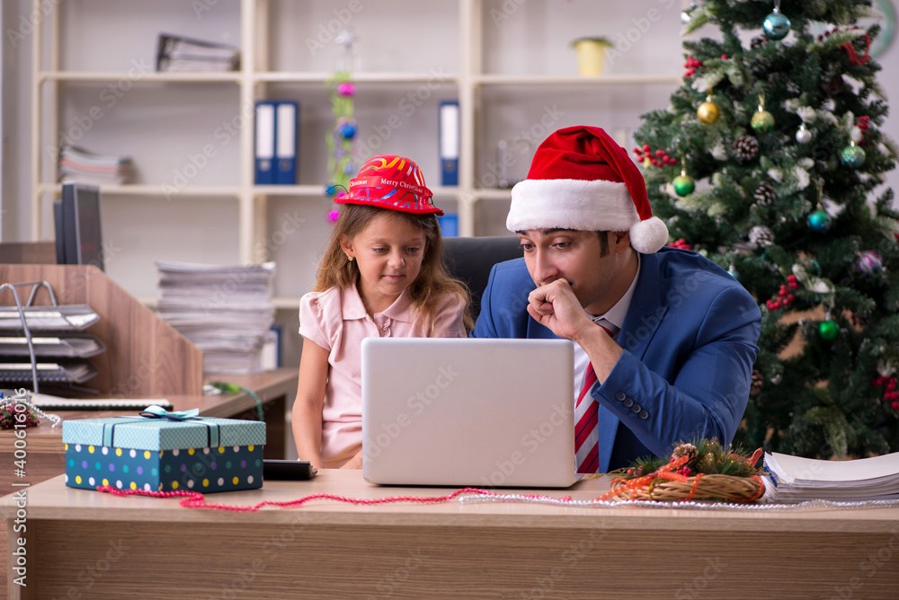 Young male employee celebrating Christmas at workplace with his Young male employee celebrating Christmas at workplace with his