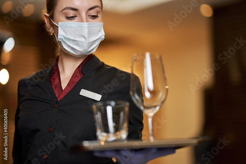 Efficient waitress using protective mask while working in cafe