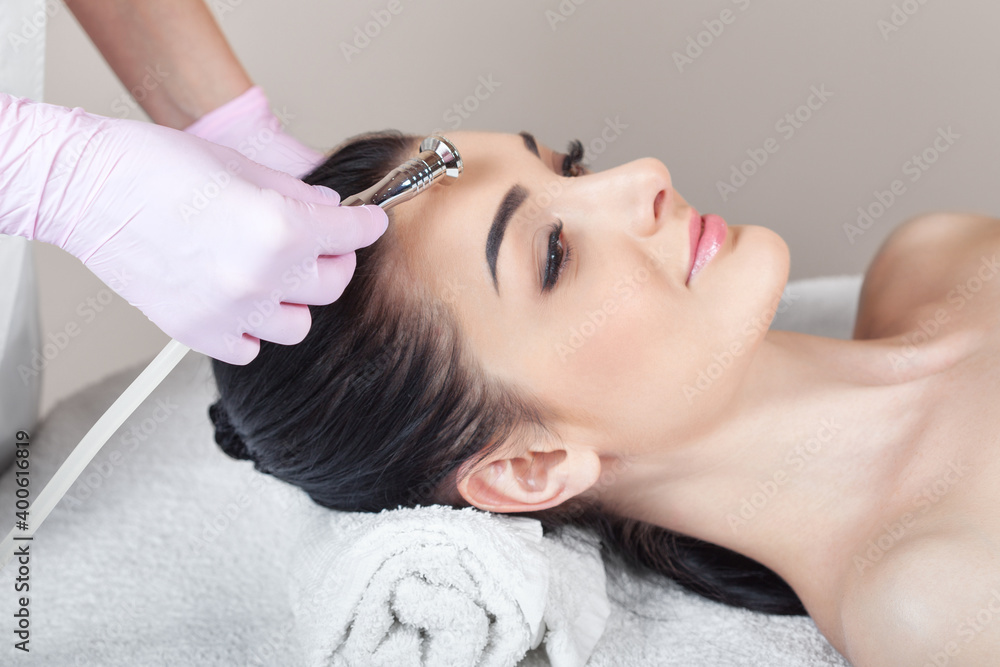 Naklejka premium The cosmetologist makes the procedure Microdermabrasion of the face skin of a beautiful girl in a beauty salon.Cosmetology and professional skin care.