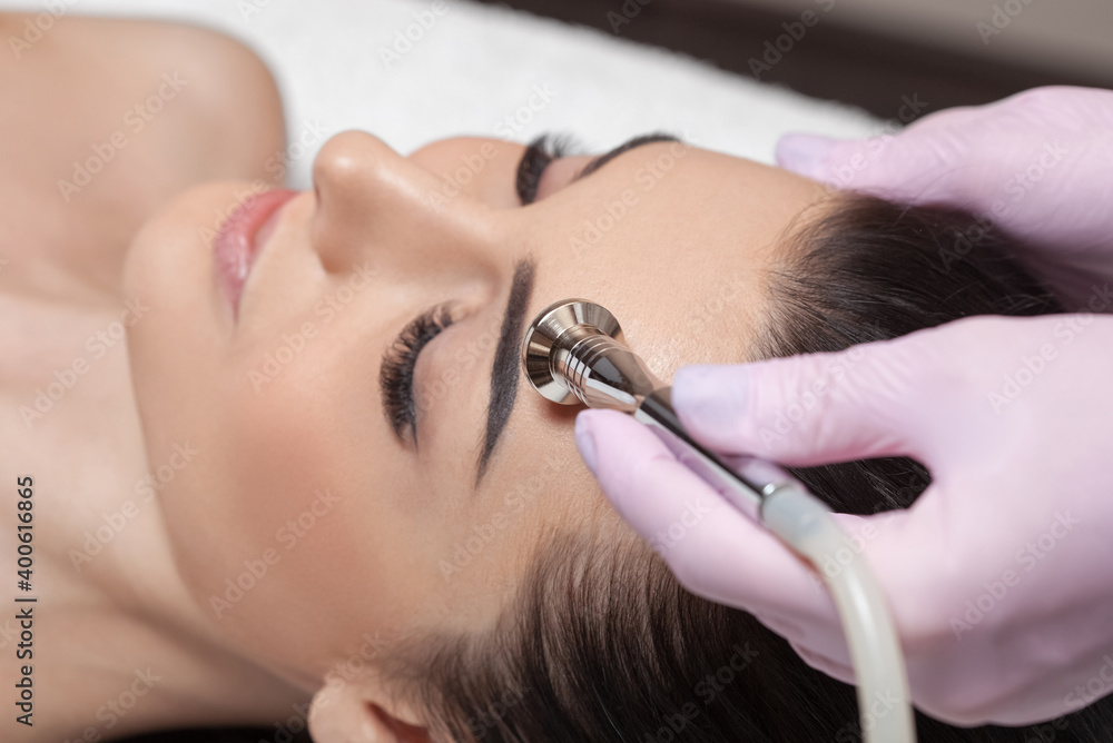 Naklejka premium The cosmetologist makes the procedure Microdermabrasion of the face skin of a beautiful girl in a beauty salon.Cosmetology and professional skin care.