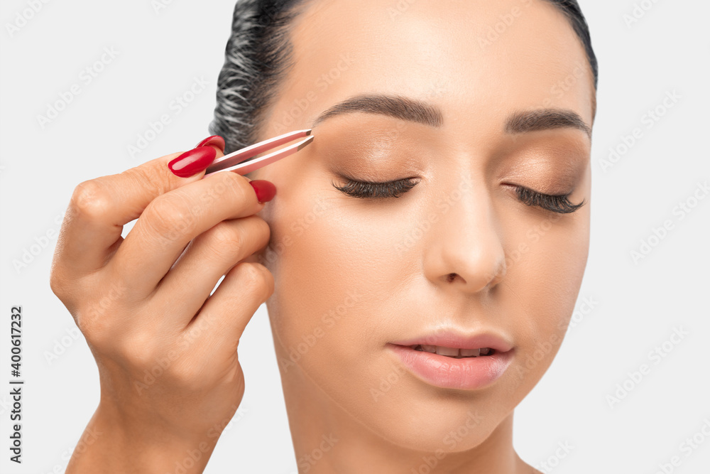 Makeup artist combs  and plucks eyebrows after dyeing in a beauty salon.Professional makeup and cosmetology skin care.