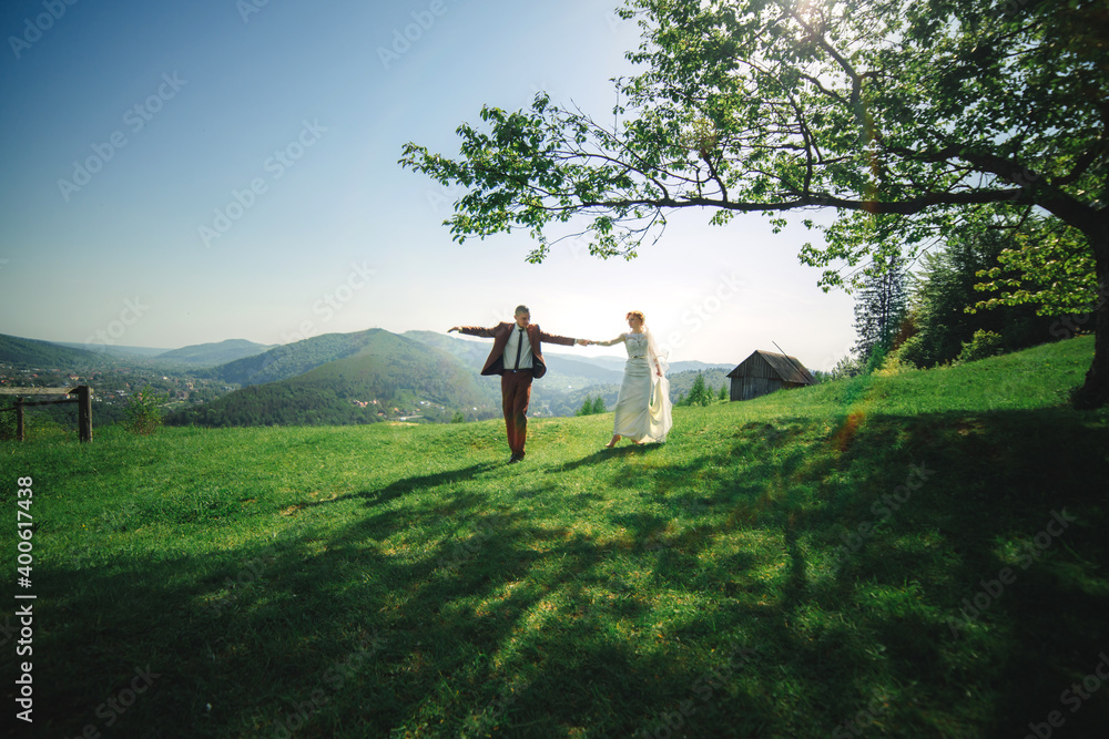 happy stylish bride and groom running and having fun in mountains on summer sunny day. gorgeous newlywed couple laughing, true feelings. emotional romantic moment. happy stylish bride and groom running and having fun in mountains on summer sunny day. gorgeous newlywed couple laughing, true feelings. emotional romantic moment.