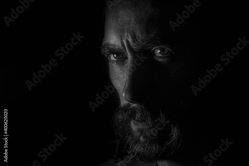 rostro en primer plano de perfil observando la camara. en blanco y negro con fondo negro oscuro  
