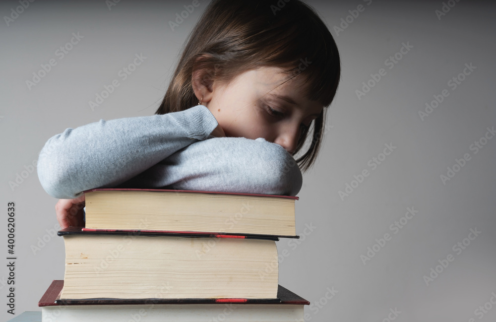 Young beautiful child girl sitting with books as symbol of learning and knowledge. Free copy space for text or design. Young beautiful child girl sitting with books as symbol of learning and knowledge. Free copy space for text or design.