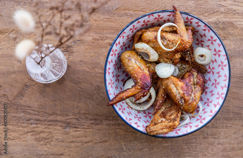 Baked pickled chicken wings with Spices and Onion in a japanese bowl on wooden background. Top view, Copy space, Selective focus.
