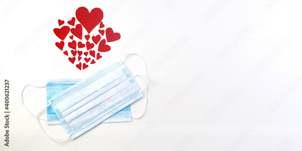 Two disposable protective covid face masks with red hearts on a white background. Safe Valentine s day concept during coronavirus pandemic and social distancing . flat lay Two disposable protective covid face masks with red hearts on a white background. Safe Valentine s day concept during coronavirus pandemic and social distancing . flat lay