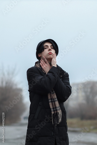 Pale guy model posing. Portrait of a young guy. Gray gloomy day, gray shades create a unique atmosphere. Dark romance.