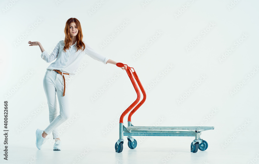 woman courier with cargo trolley on light background