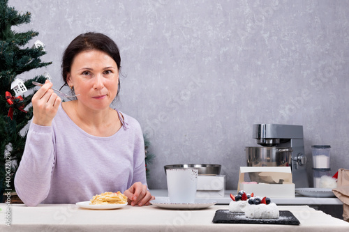 Woman housewife eats dessert in kitchen. Portrait of woman drinking tea