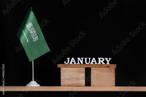 Wooden calendar of January with Saudi Arabia flag on black background. Dates of Saudi Arabia in January