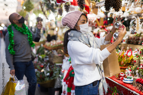 Woman in protective mask chooses christmas balls at christmas street fair