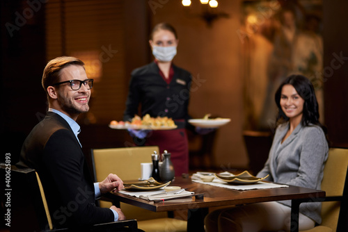 Lovely couple at restaurant table being served by responsible waitress