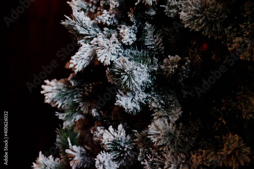 Close-up of Christmas or happy new year tree with decorative elements and artificial snow. Selective focus of Christmas tree in the living room interior. Concept of stylish backgrounds. Copy space