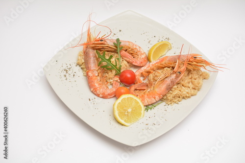 Large shrimps on a white plate. Decorated with lemon wedges. Located on a white background. Can be used in the restaurant menu.