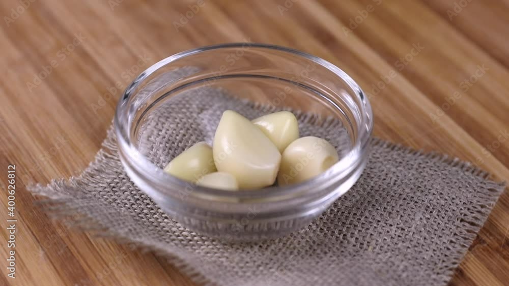 peeled cloves of garlic rotating close-up on wooden background peeled cloves of garlic rotating close-up on wooden background