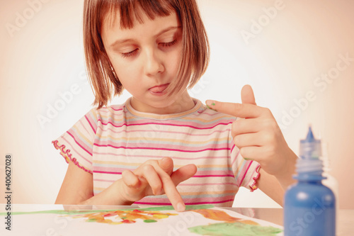 Art and fun leisure time of female child. Portrait of beautiful young girl painting picture with hands.