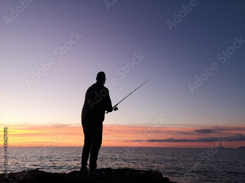 Fisherman fishing at sunset, only see the silhouette. 