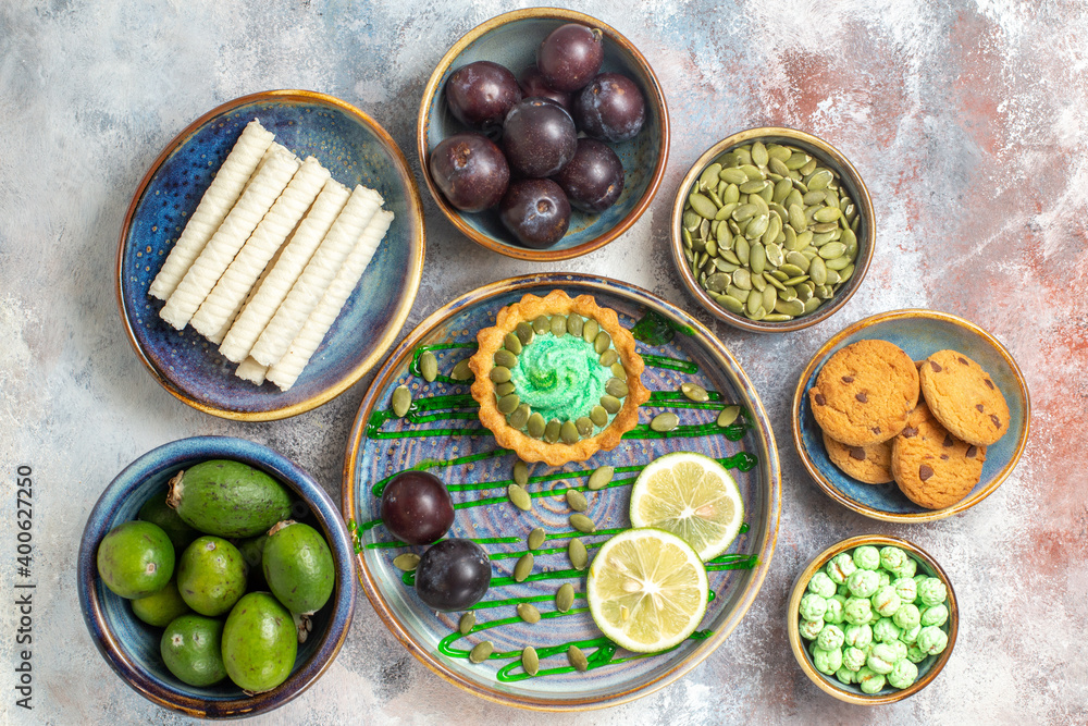 Top down view charming yummy snack with biscuits ripe plums feykhoas sweeties on pink surface with free space Top down view charming yummy snack with biscuits ripe plums feykhoas sweeties on pink surface with free space