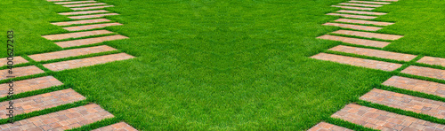 Landscaping lawn with green grass. Curved stone pathway leading through lawn. Path in garden.