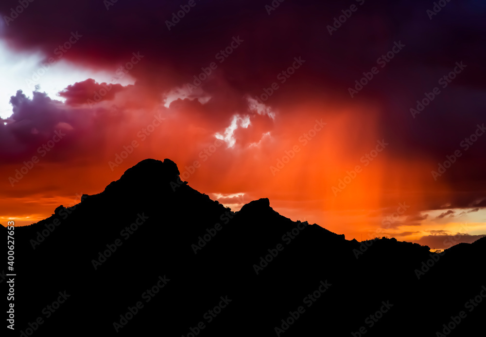 Arizona Monsoon Sunset with Purple and Orange Rain and Black Mountain Silhouette