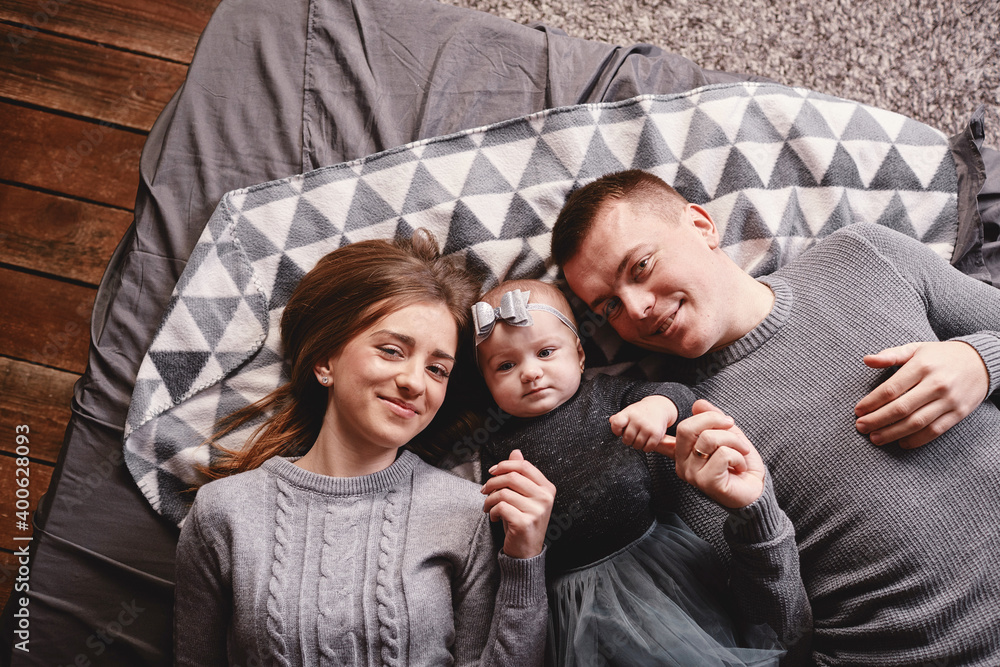 High angle view of a couple of attractive young parents lying in a bed with their cute baby girl. happy holiday.